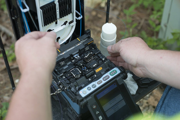 Technician fusion splicing fiber inside an outdoor plant closure