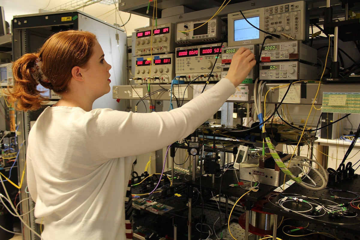 Engineer adjusting an optical power meter on a fiber communications testbed