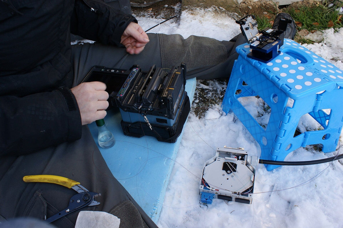 Technician fusion splicing fiber outdoors with a core-alignment splicer