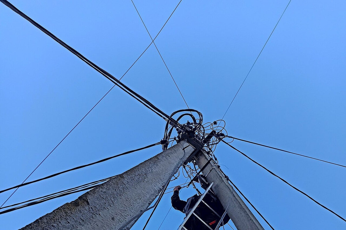 Aerial fiber plant technician working on a pole during network testing